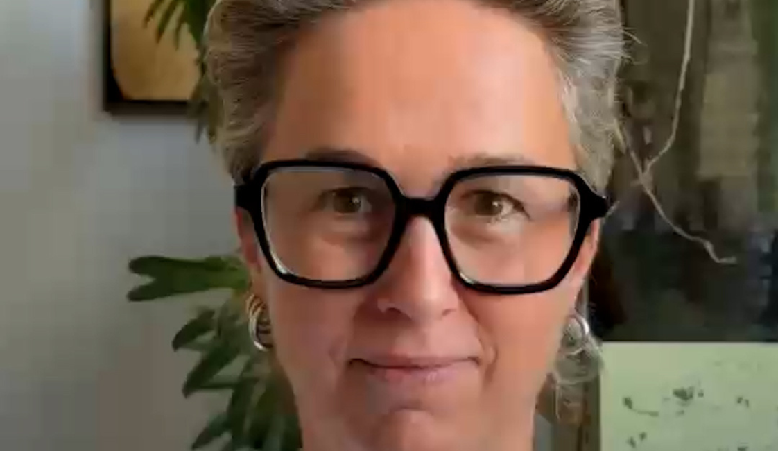 Person mit kurzen grauen Haaren und großer schwarzer Brille vor grünen Zimmerpflanzen. Rechts oben steht „Meine Würde“.