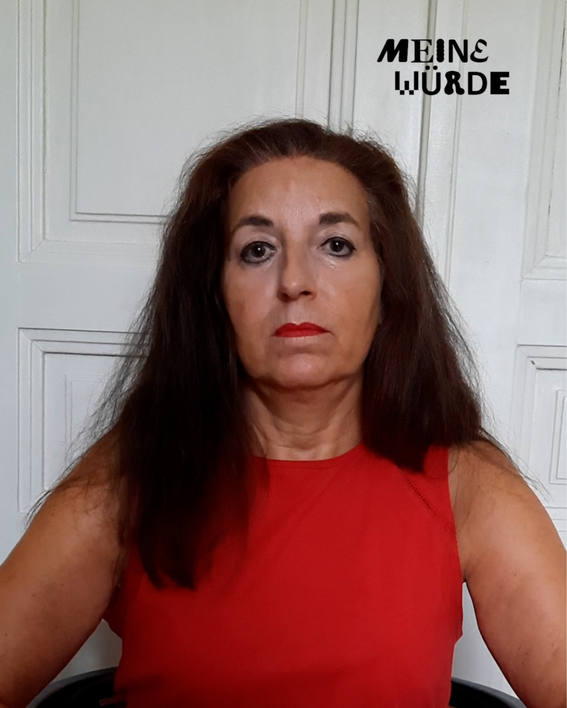 Person mit langen dunklen Haaren und rotem ärmellosem Oberteil, frontal vor einem hellen Hintergrund sitzend. Rechts oben steht „Meine Würde“.